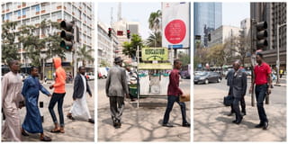 An image of men walking across a busy street, with tall buildings in the background. 